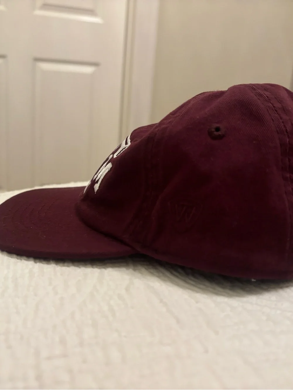 A&M baby baseball cap, elastic back w/ white embroidered A&M Logo & Lil’Aggie